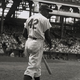 American baseball player Jackie Robinson, second baseman for the Brooklyn Dodgers, steps up to bat with his back to the camera during a game at a packed stadium.